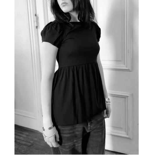 Model in black tee standing in front of a door
