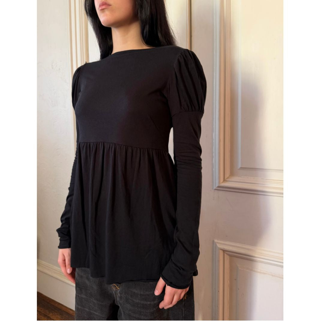 Person wearing a black long-sleeve top with a soft texture in an indoor setting.