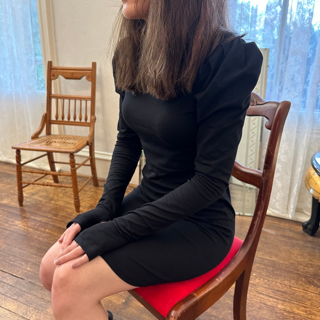 Model wearing la fae dress, seated in a chair